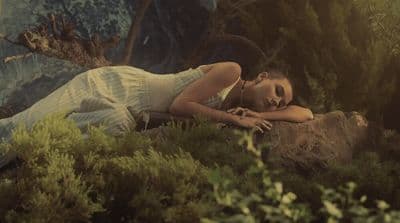 a woman laying on a rock in a forest