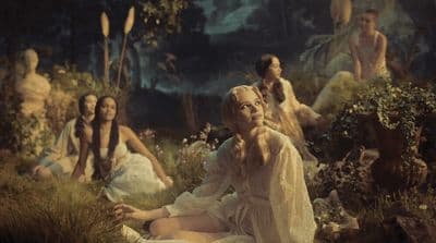 a group of women sitting on the ground in a forest