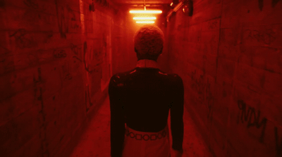a person walking down a dark hallway with graffiti on the walls