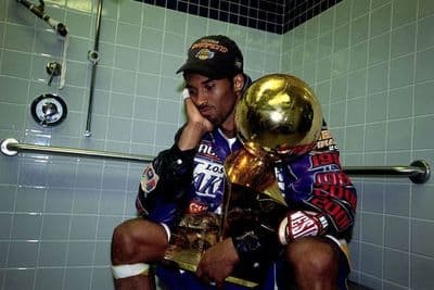 a man sitting on a toilet holding a trophy