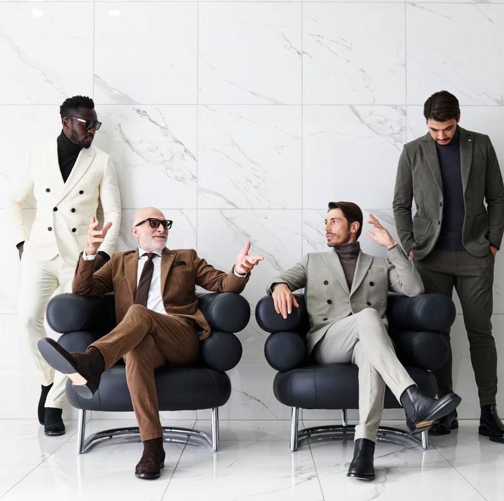 a group of men sitting in chairs in front of a wall