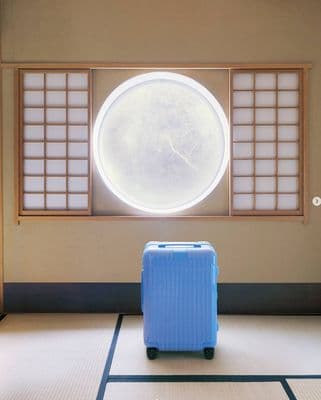 a blue suitcase sitting in front of a window