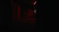 a dark hallway with a red light at the end of it