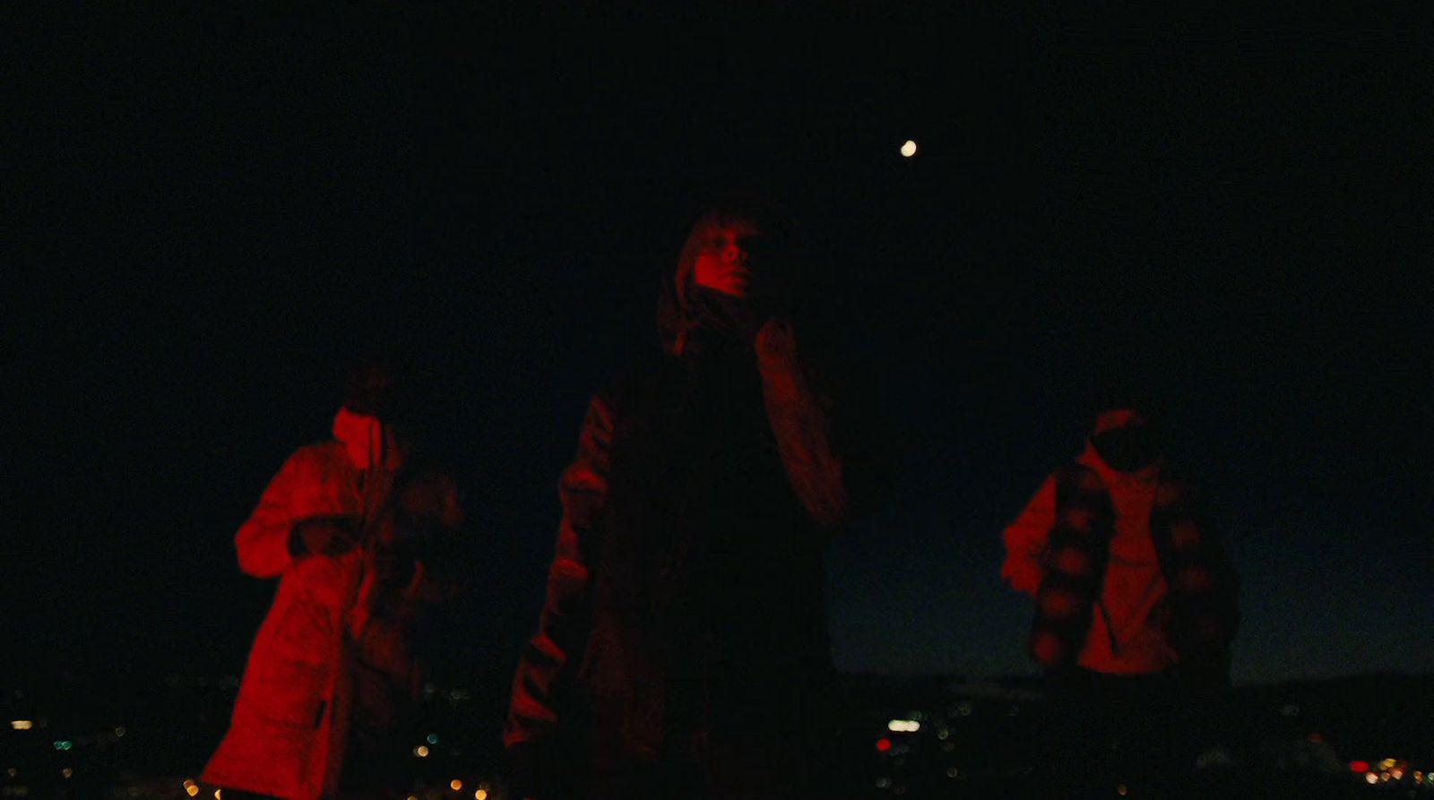 three people standing in the dark at night
