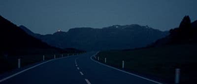 an empty road with mountains in the background