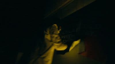 a person standing in the dark holding a skateboard