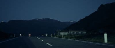 a car driving down a road with mountains in the background