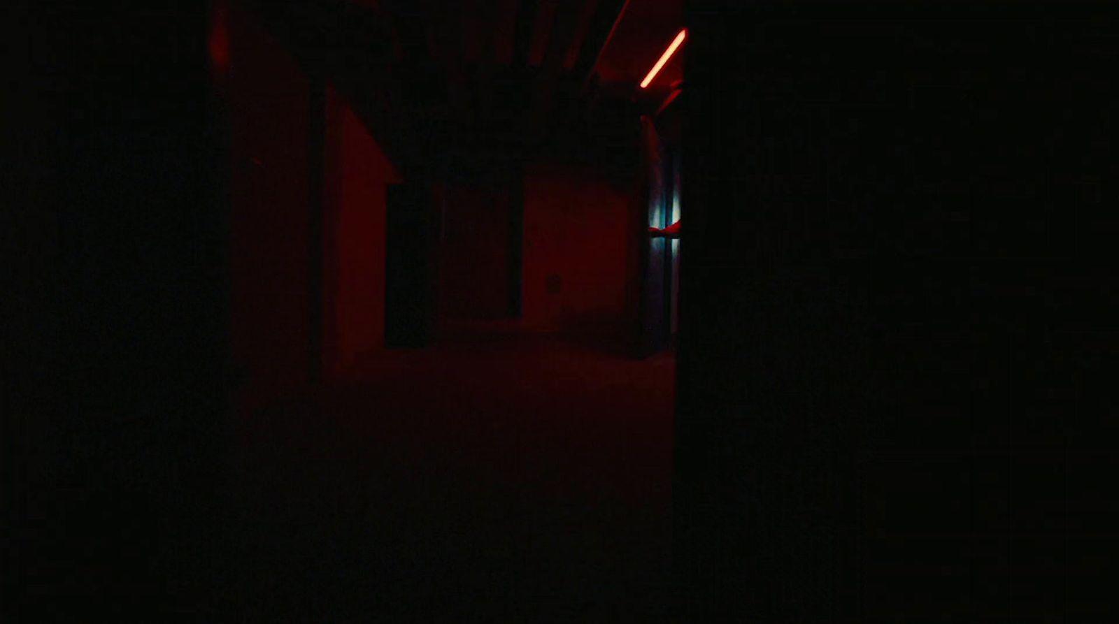 a dark hallway with a red light at the end