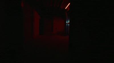 a dark hallway with a red light at the end