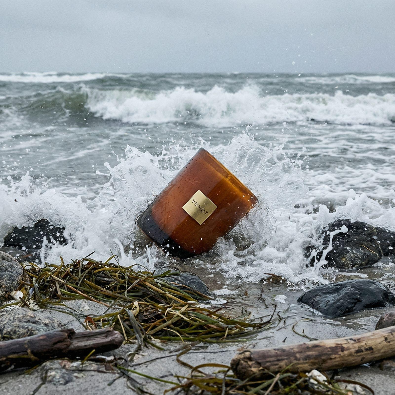 a bottle of wine sitting on top of a beach next to the ocean