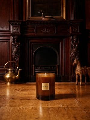 a candle sitting on the floor in front of a fireplace