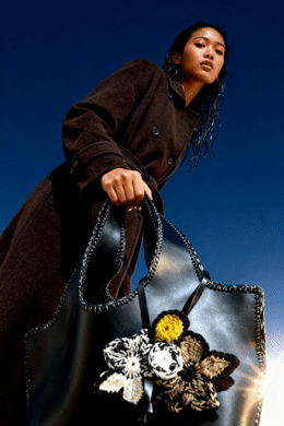 a woman holding a black purse with flowers on it