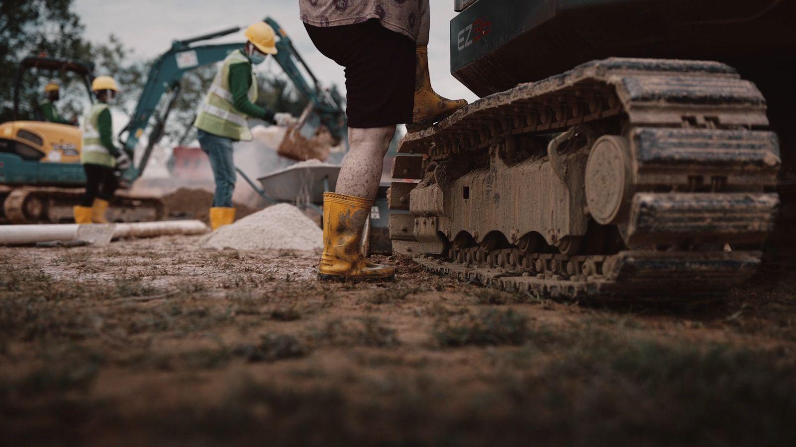 a man standing next to a bulldozer on top of a field