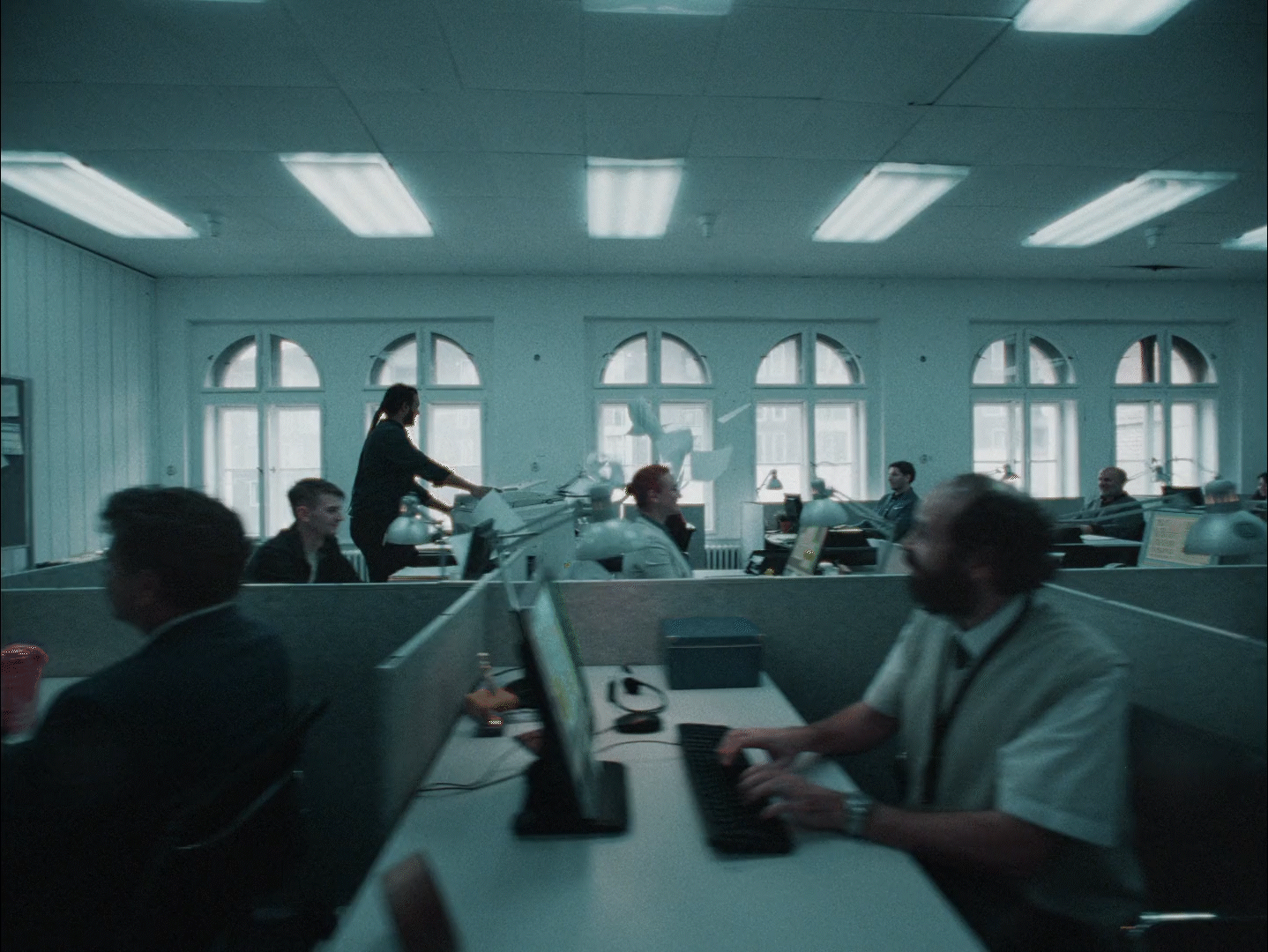 a group of people sitting at desks in an office