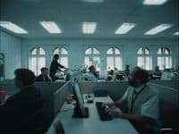 a group of people sitting at desks in an office