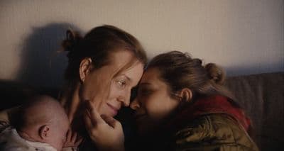 a woman holding a baby next to a woman holding a baby