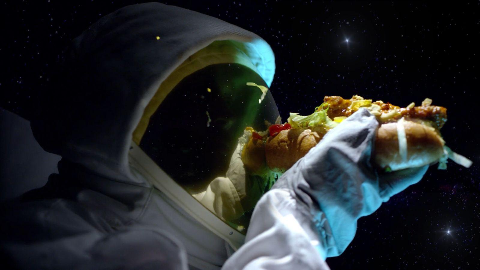 a person in a space suit holding a hot dog