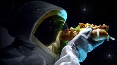 a person in a space suit holding a hot dog