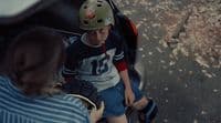 a young boy sitting on a scooter with a helmet on