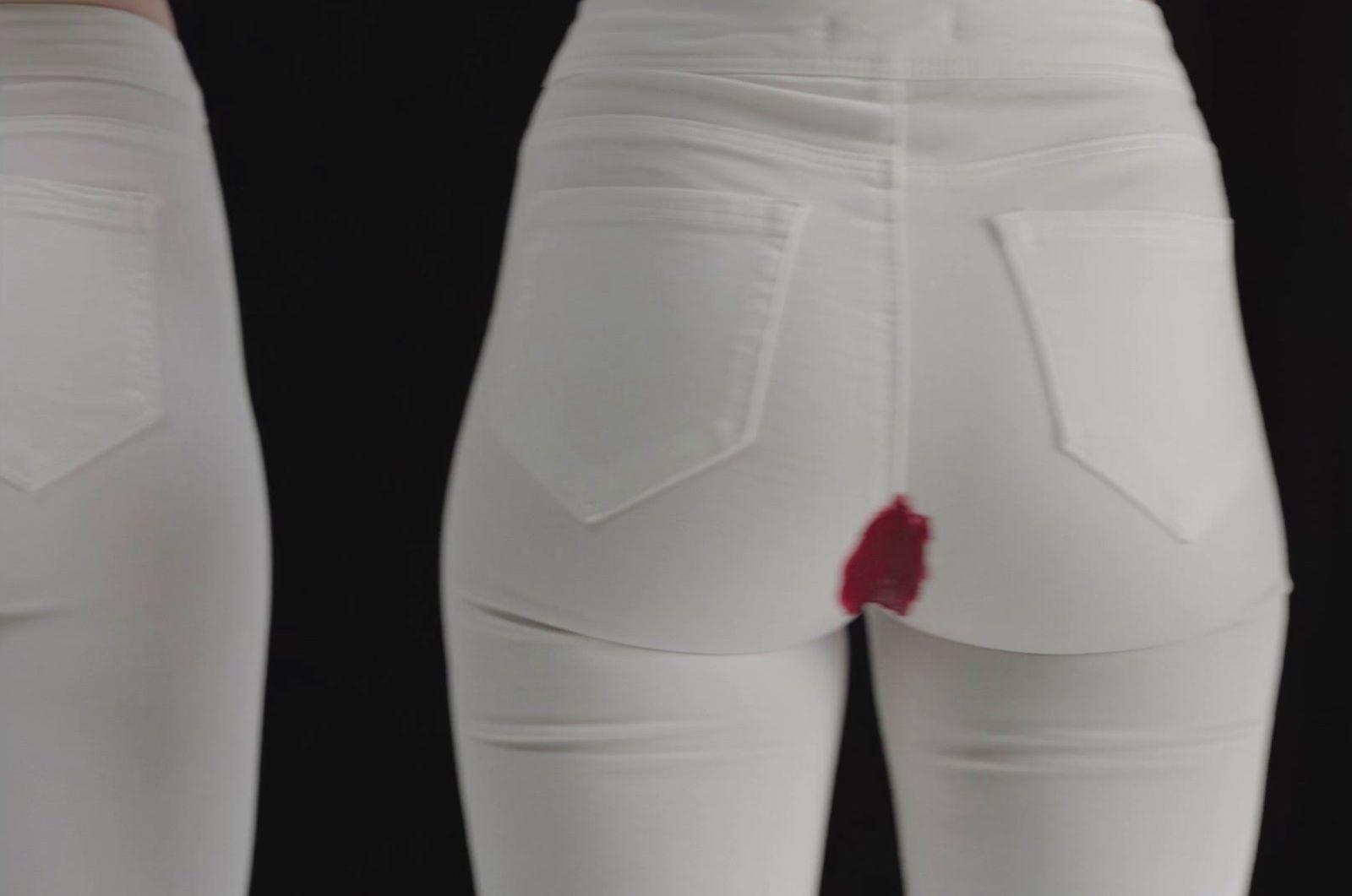 a pair of white jeans with a red patch on the side