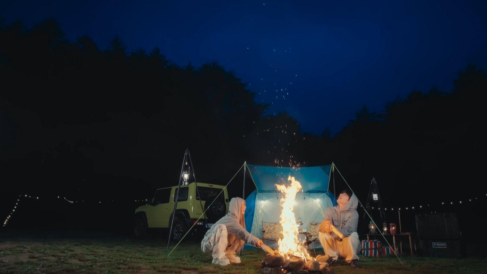 two people sitting around a campfire at night