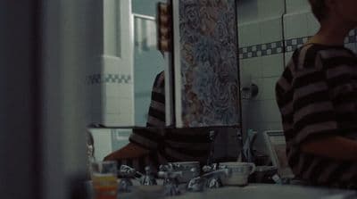 a young boy standing in front of a bathroom mirror