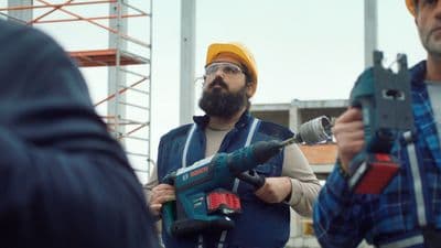 a man holding a drill and a cordless drill
