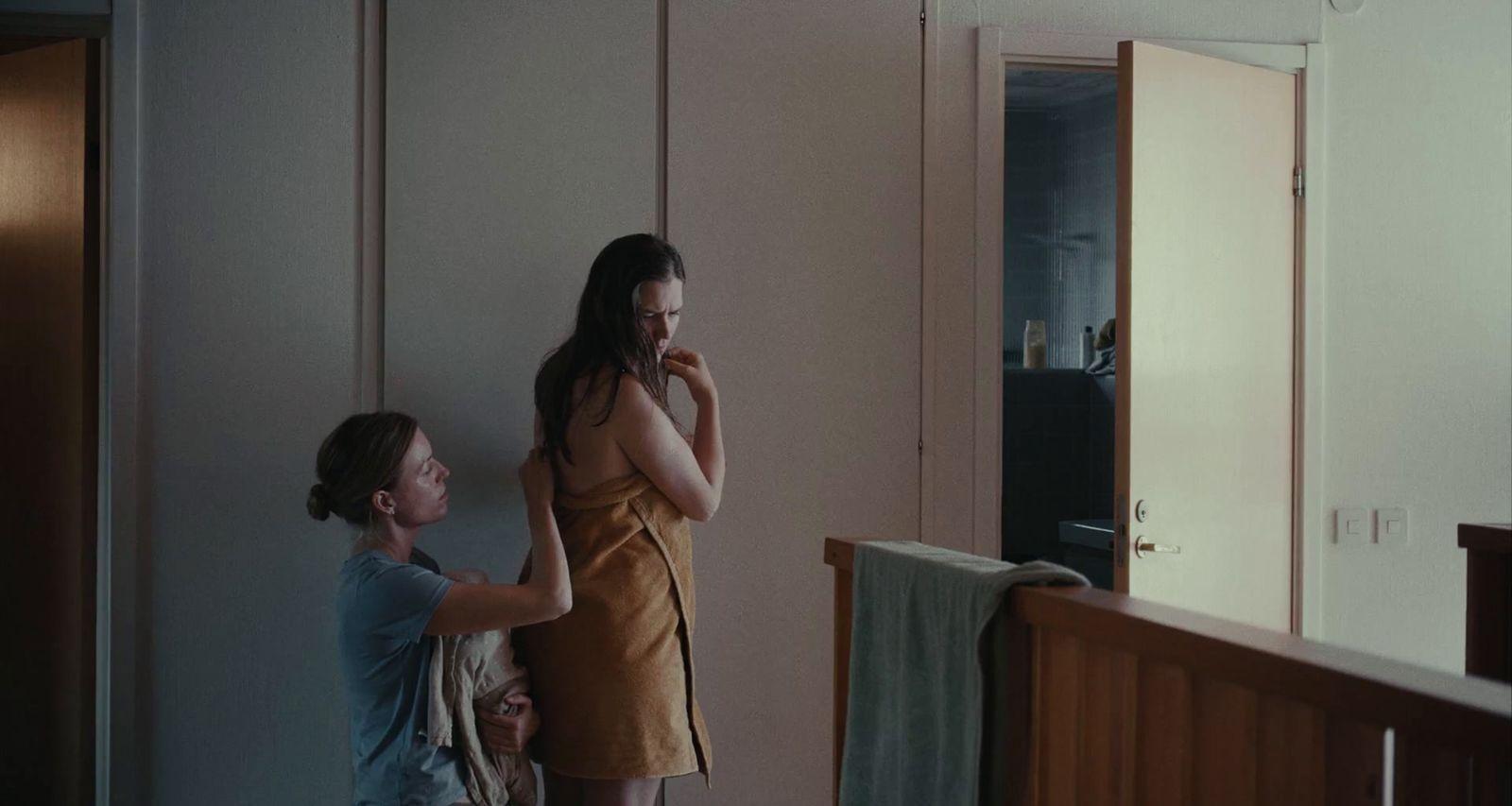 a woman standing next to a woman brushing her teeth