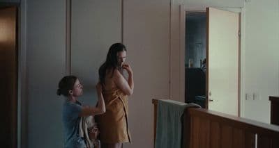 a woman standing next to a woman brushing her teeth