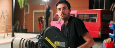a man holding a camera in front of a red double decker bus