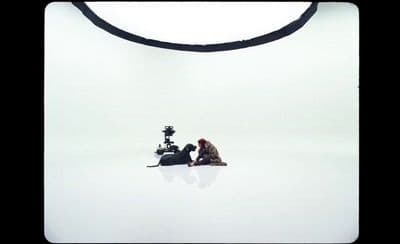 a man and a woman sitting on the ground in front of a camera