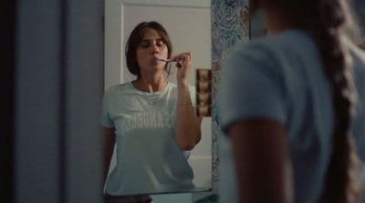 a woman brushing her teeth in front of a mirror