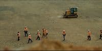 a group of people walking across a dirt field