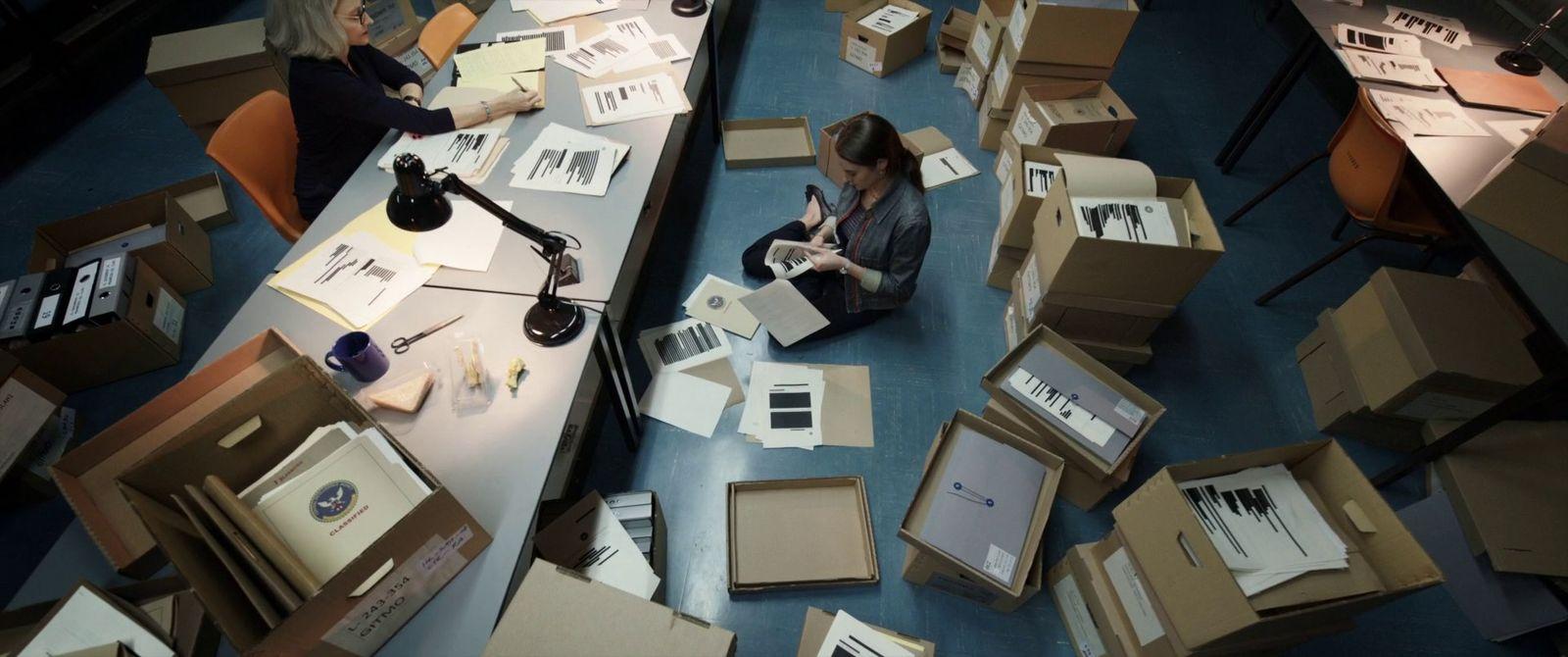 a woman sitting on the floor surrounded by boxes