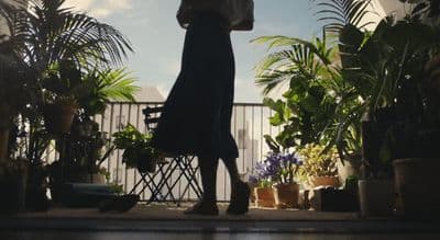 a woman holding an umbrella standing in front of potted plants