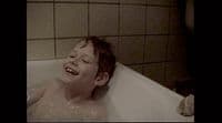 a young boy is laughing in a bathtub