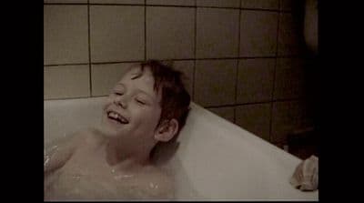 a young boy is laughing in a bathtub