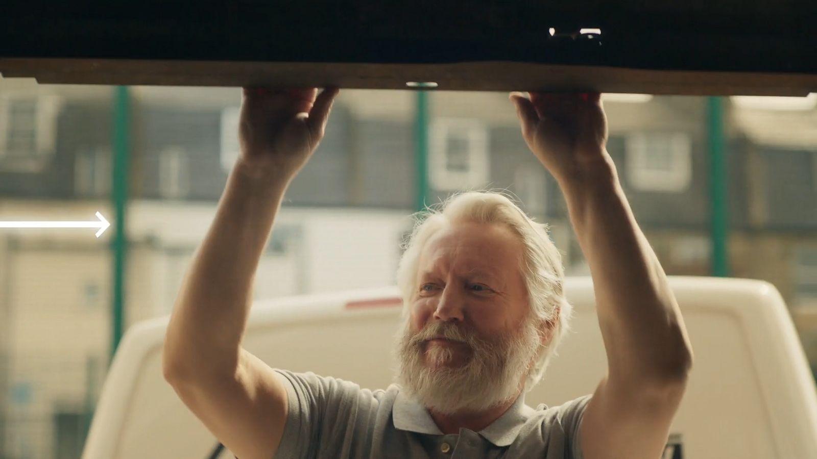 a man with a white beard is holding a piece of wood above his head
