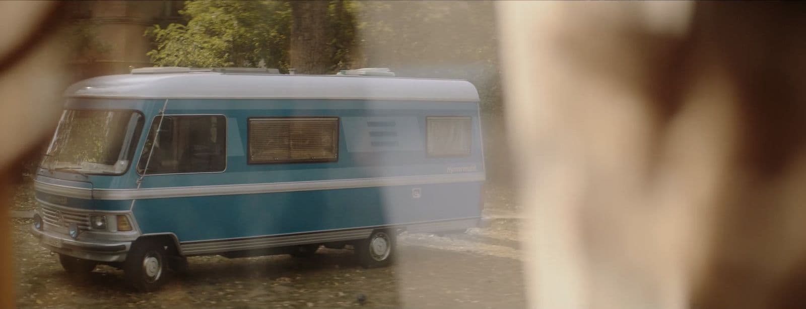 a blue and white camper parked in front of a house