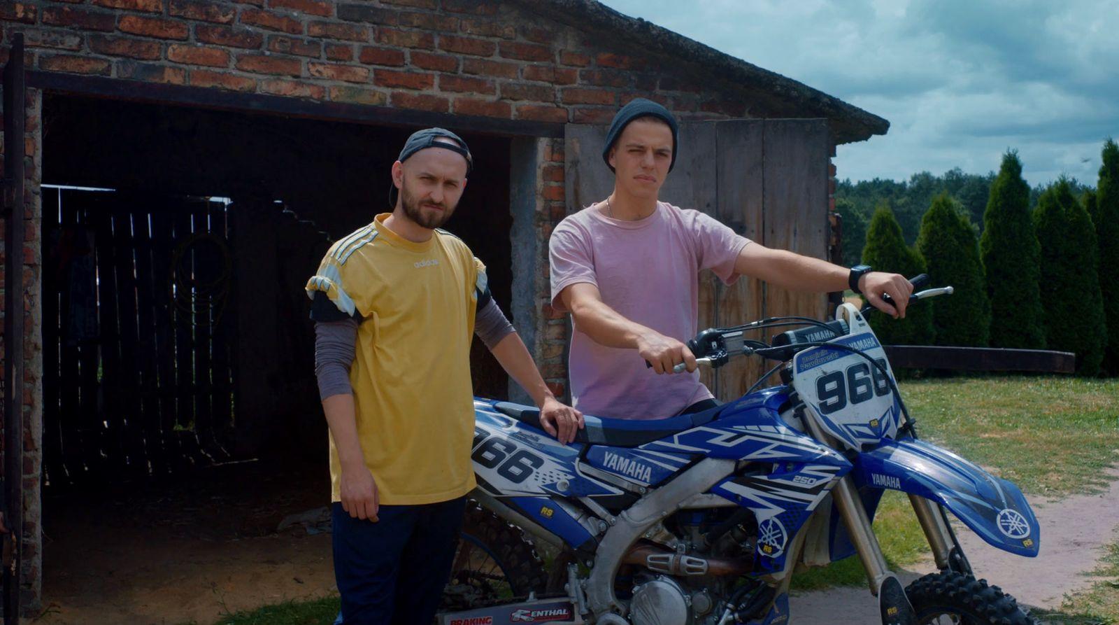 a couple of men standing next to a dirt bike