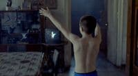 a shirtless man standing in a living room next to a table