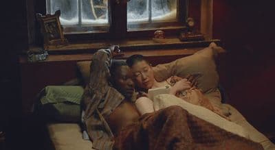 a couple of people laying in a bed next to each other