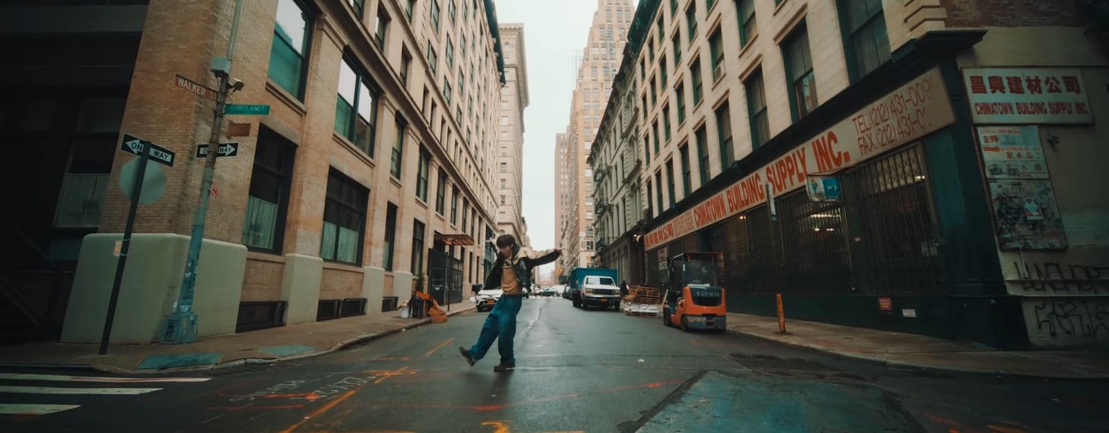 a man walking down a street next to tall buildings
