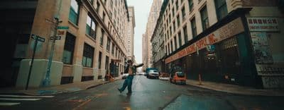 a man walking down a street next to tall buildings