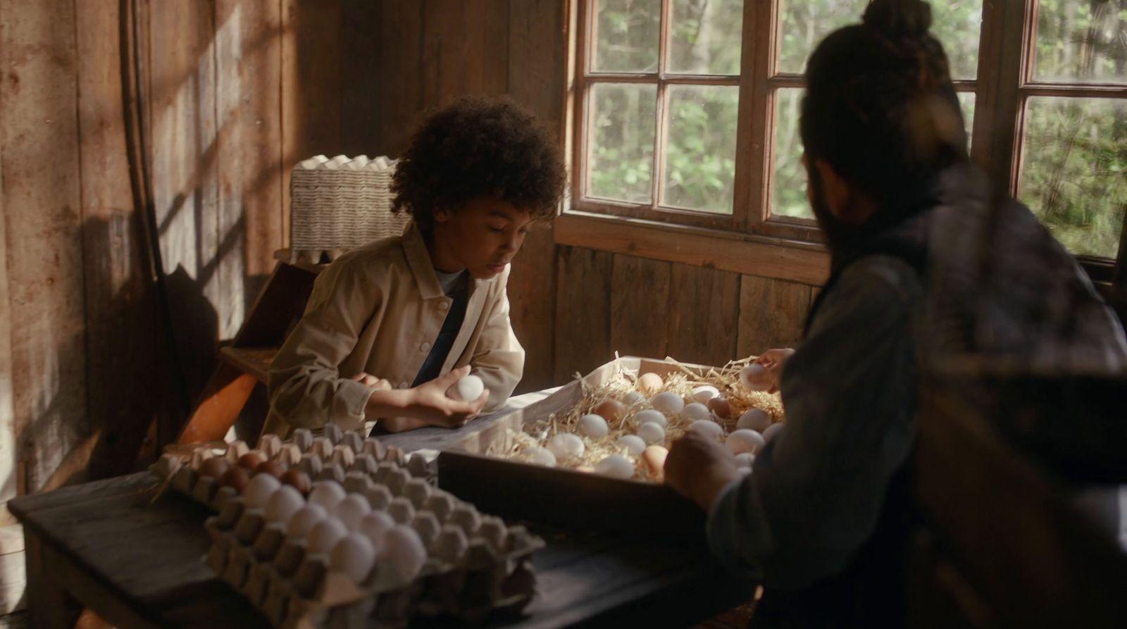 a woman sitting at a table with a tray of eggs