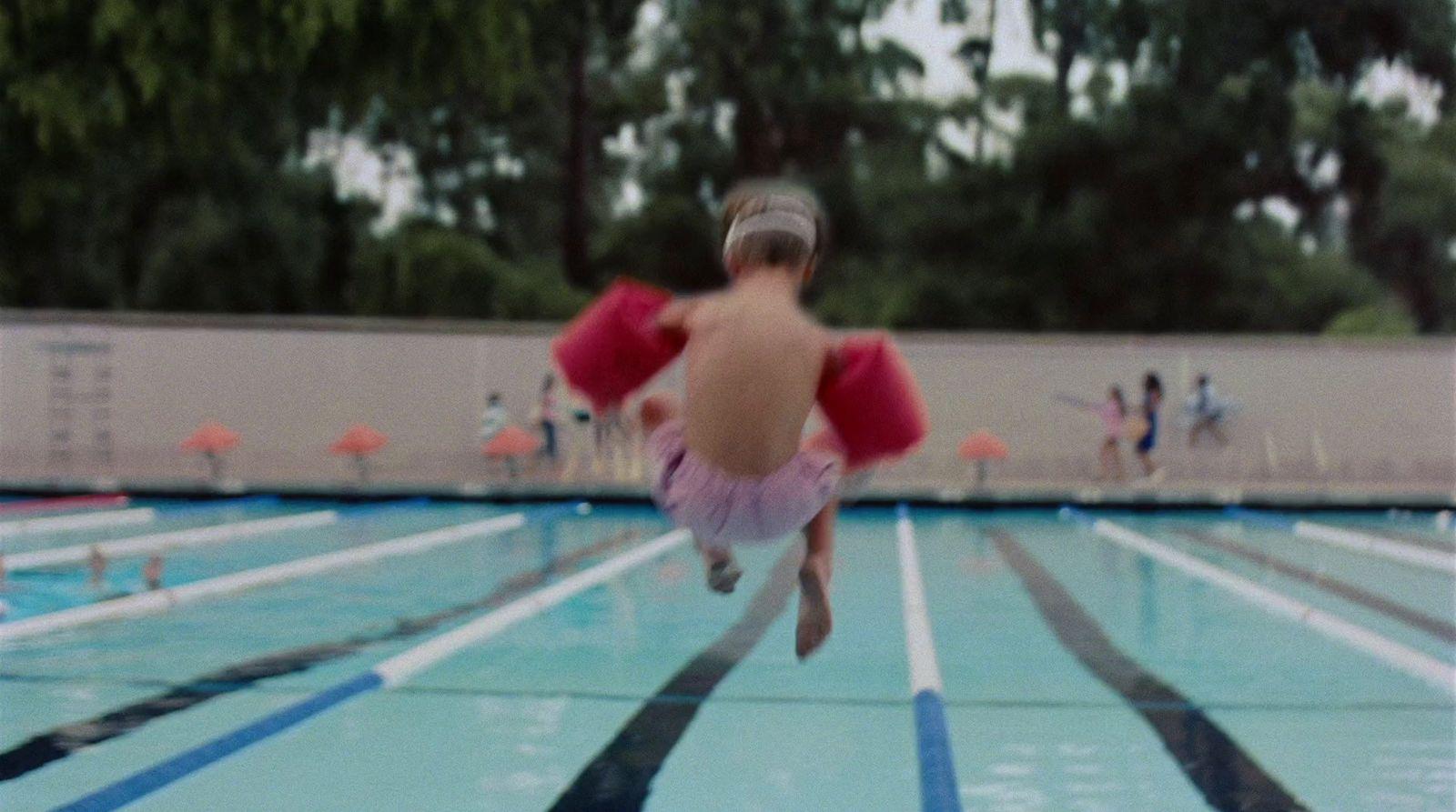 a little girl that is in the air in a swimming pool