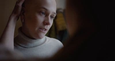 a woman with a bald head is looking in the mirror