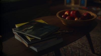 a wooden table topped with books and a bowl of apples