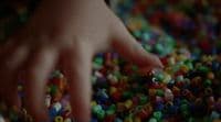 a hand reaching for a pile of colorful beads