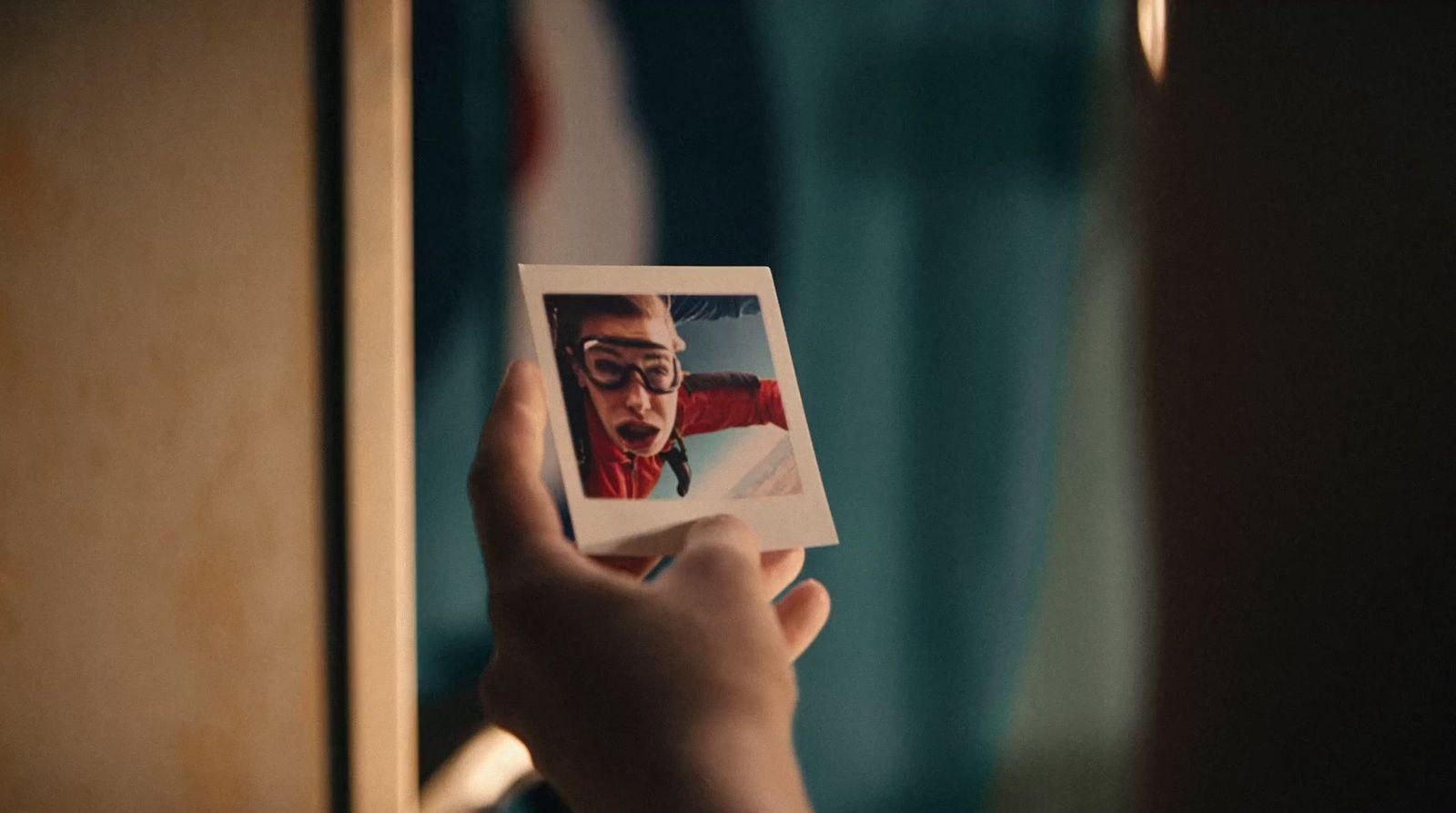 a person holding a polaroid with a picture of a man